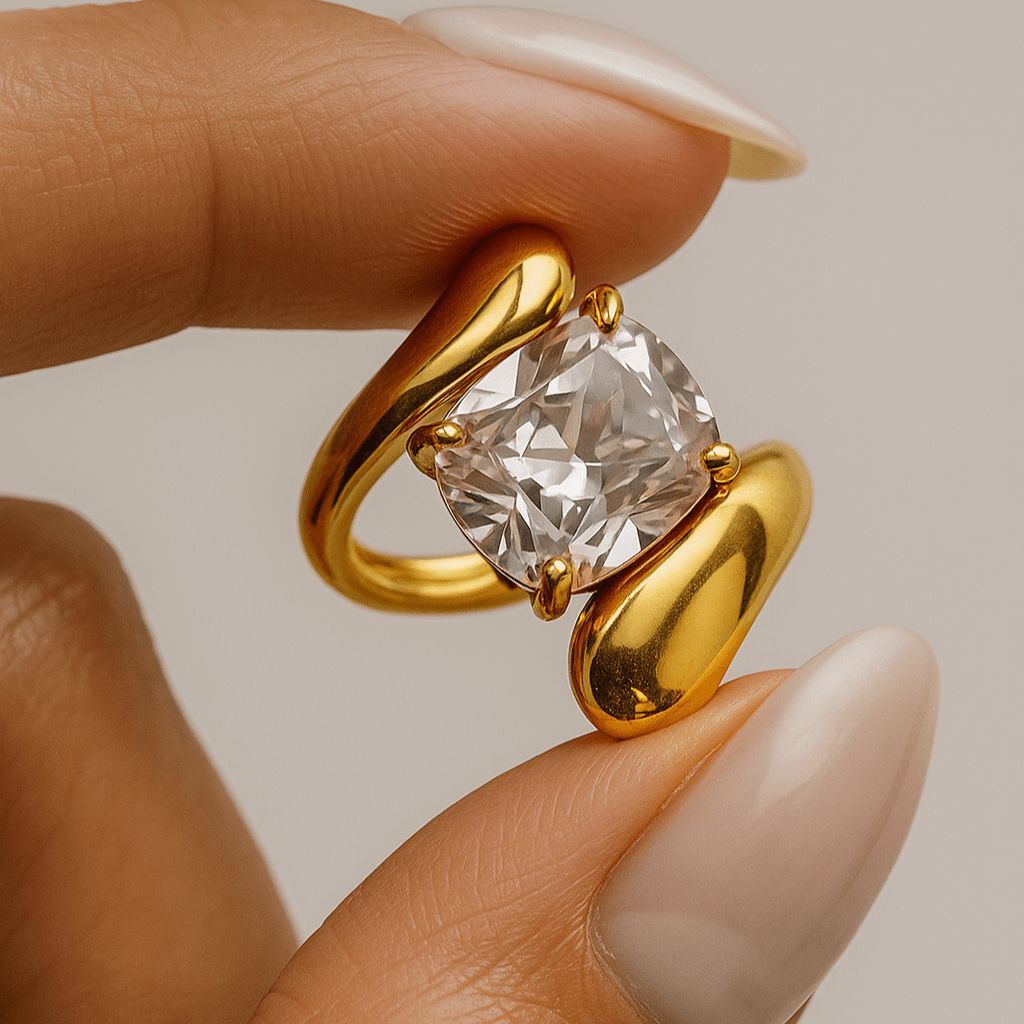 Gold ring with a large diamond held between fingers against a neutral background