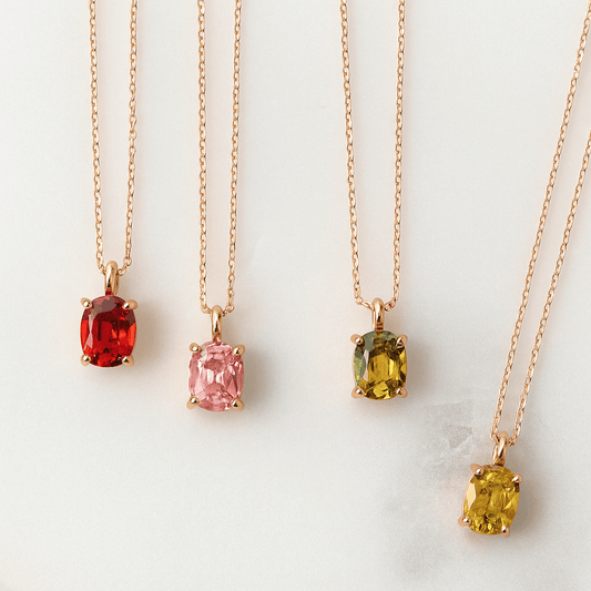 Four gold necklaces with colored gemstones on a white background