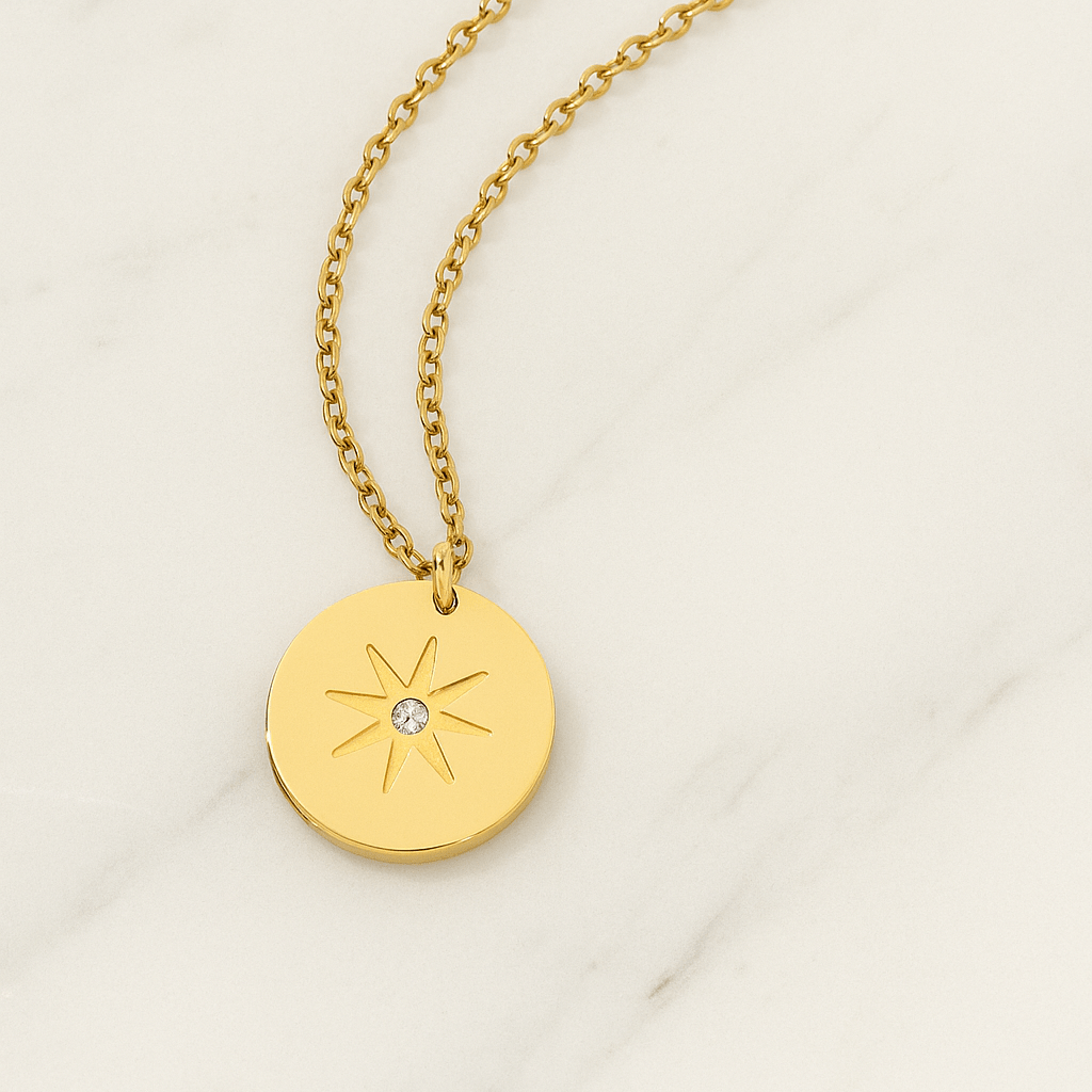 Gold necklace with a round pendant featuring a star design on a light background