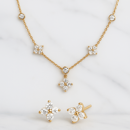 Gold necklace and earrings with diamond-like stones on a white background