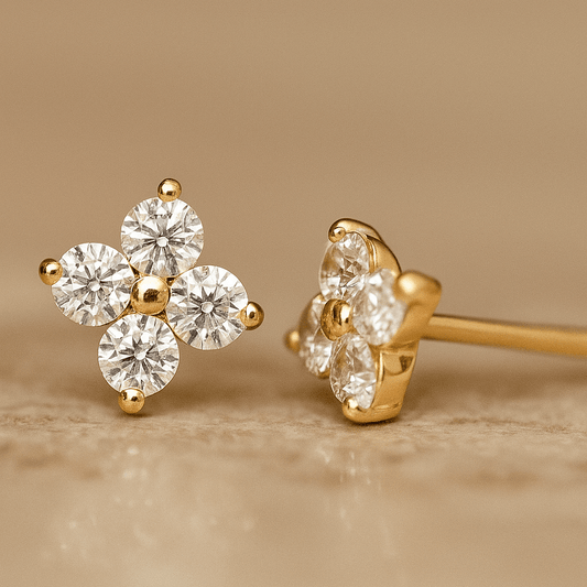 Gold earrings with clear gemstones on a beige background