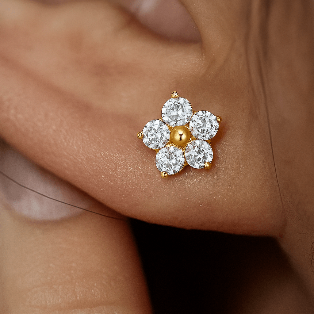 Flower-shaped earring with gold center and clear stones worn on an ear.