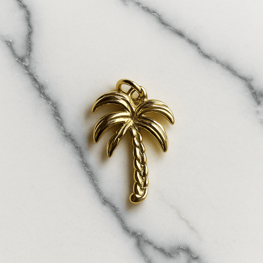 Gold palm tree charm on a marble background