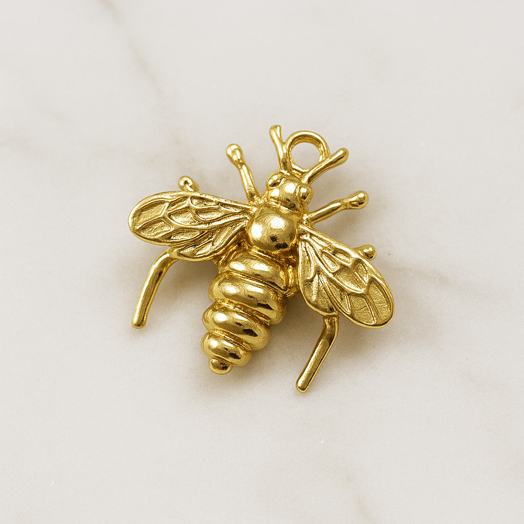 Gold bee-shaped pendant on a light beige background