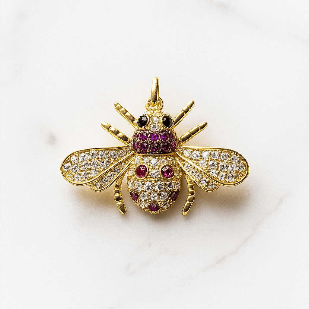 Gold bee-shaped pendant with gemstones on a white background