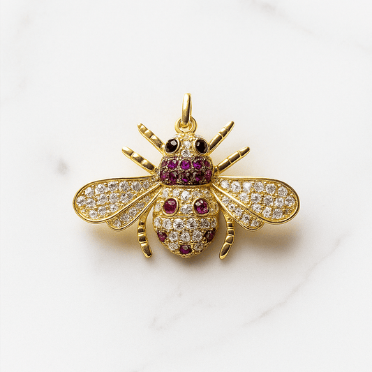 Gold bee-shaped pendant with gemstones on a white background