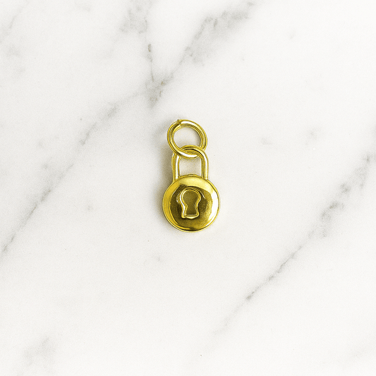 Gold padlock charm on a marble background