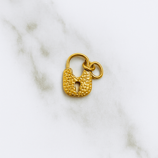 Gold padlock charm on a marble background