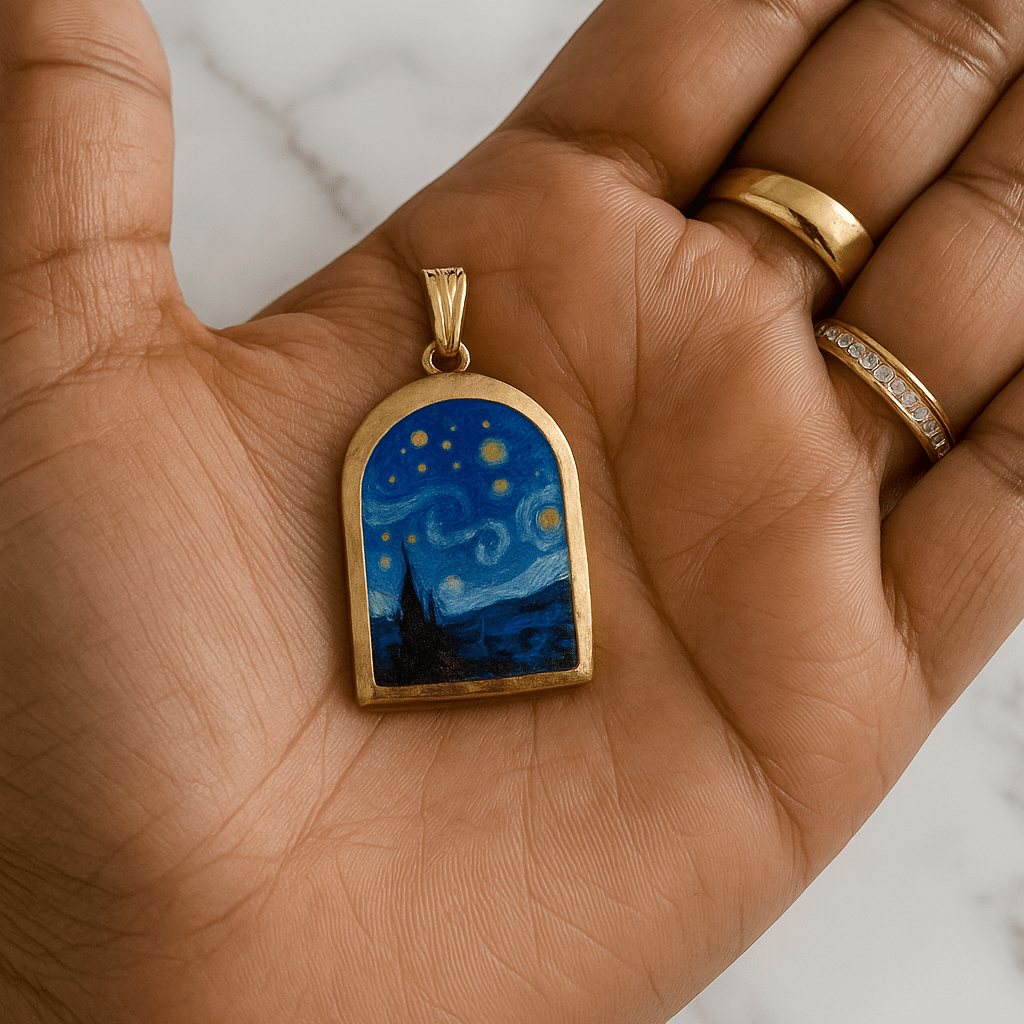 Hand holding a gold-framed pendant with a starry night design on a marble surface