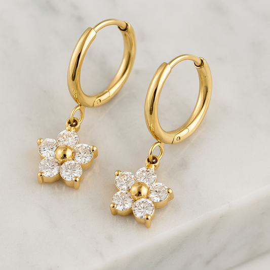 Gold hoop earrings with floral charms on a light background