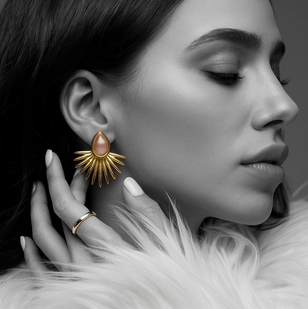 Close-up of a woman wearing a gold earring with a pink gemstone, with a blurred background.