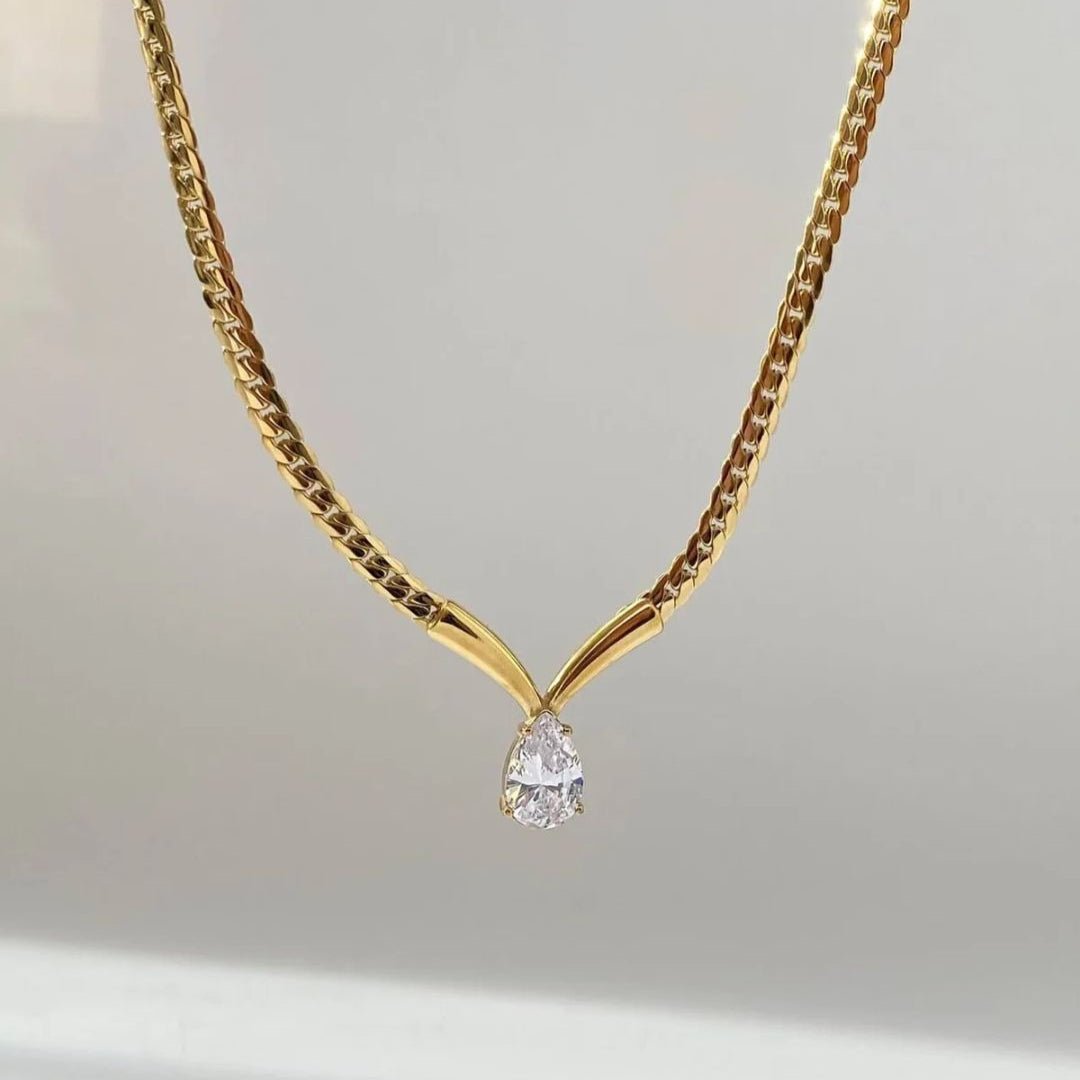 Gold necklace with a diamond pendant on a light gray background