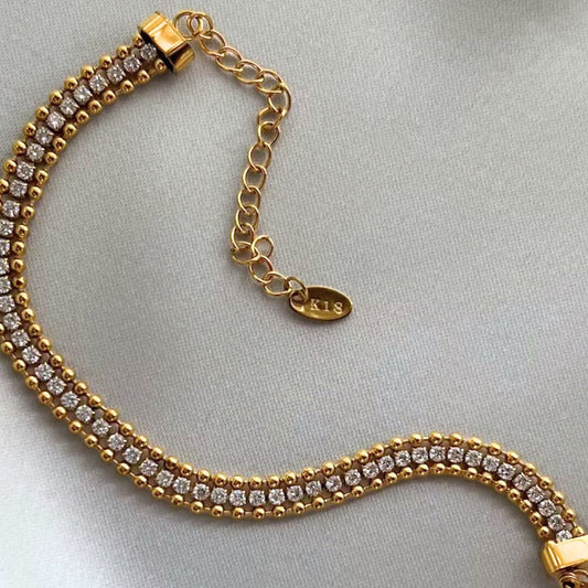 Gold bracelet with diamond accents on a light gray background