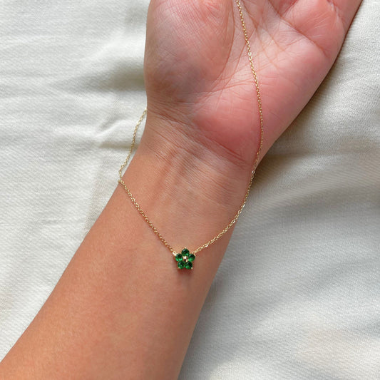 An 18k gold-dipped bee pendant necklace with a green emerald gemstone on a hand, showcasing the design and the length of the necklace.