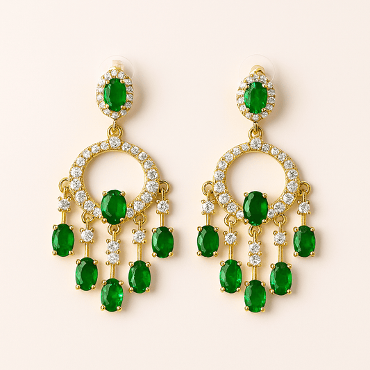 Gold earrings with green gemstones on a beige background