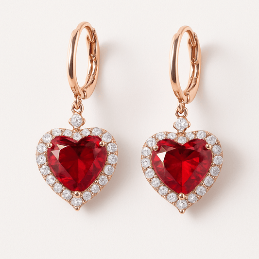 Heart-shaped red gemstone earrings with rose gold and clear stones on a white background