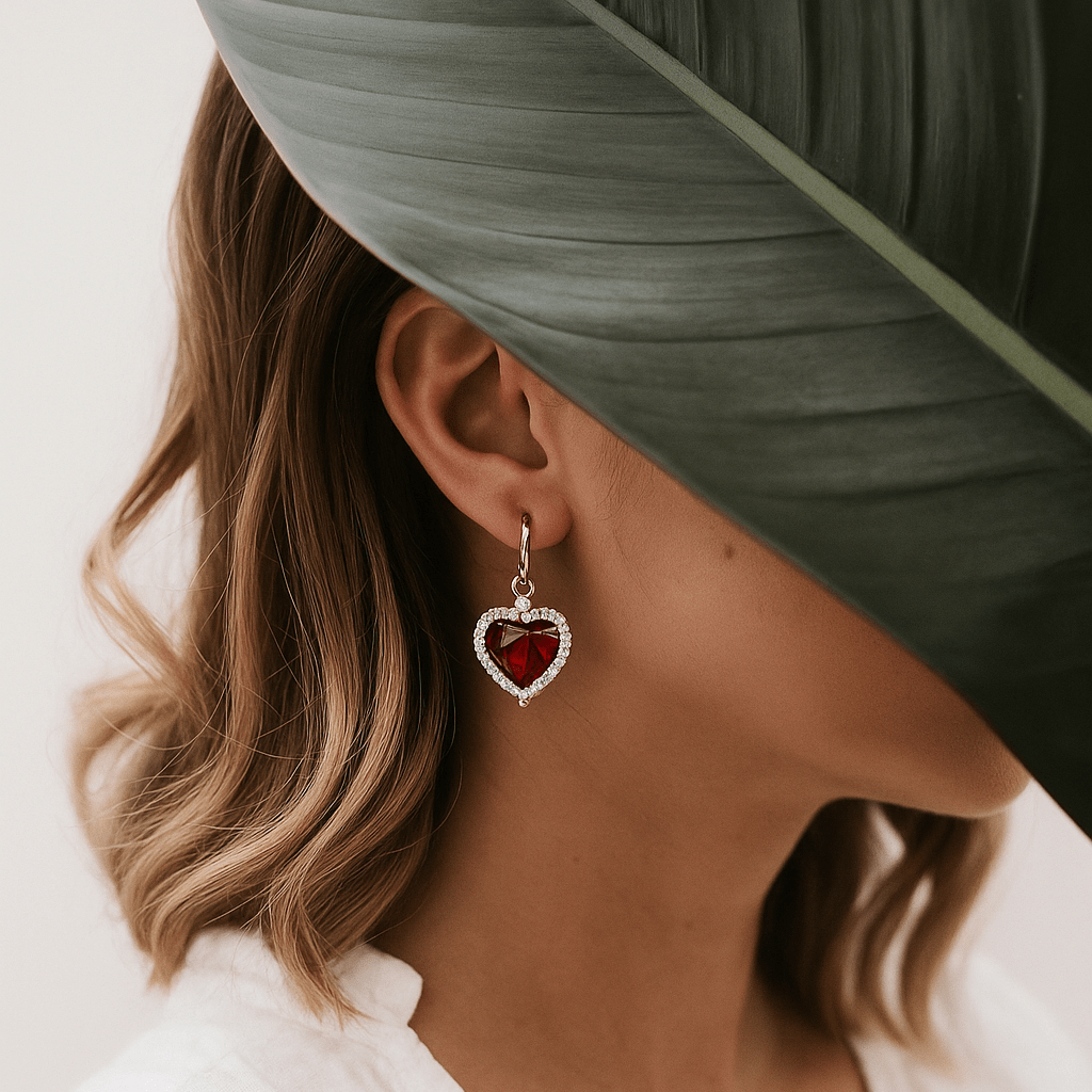 Close-up of a woman wearing a heart-shaped earring with a green leaf in the foreground
