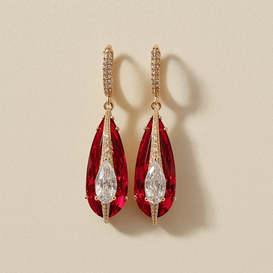 Pair of red teardrop earrings with gold accents on a beige background