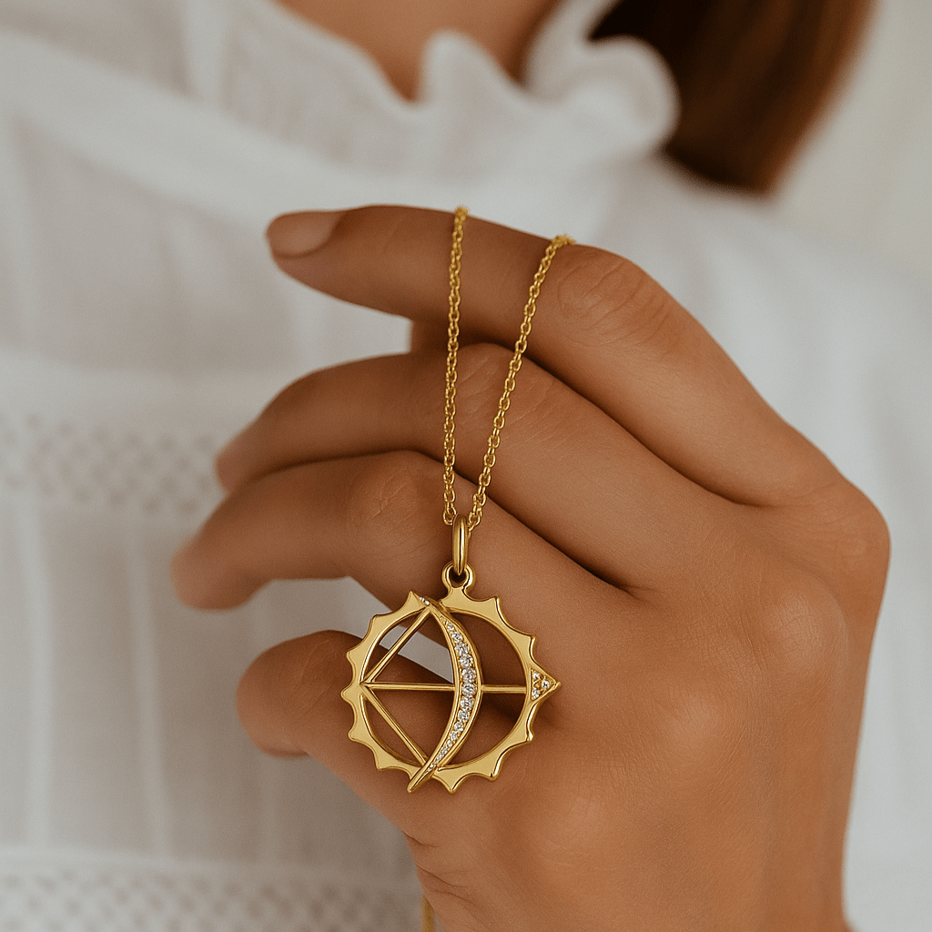 Gold necklace with a unique pendant held by a hand against a white background