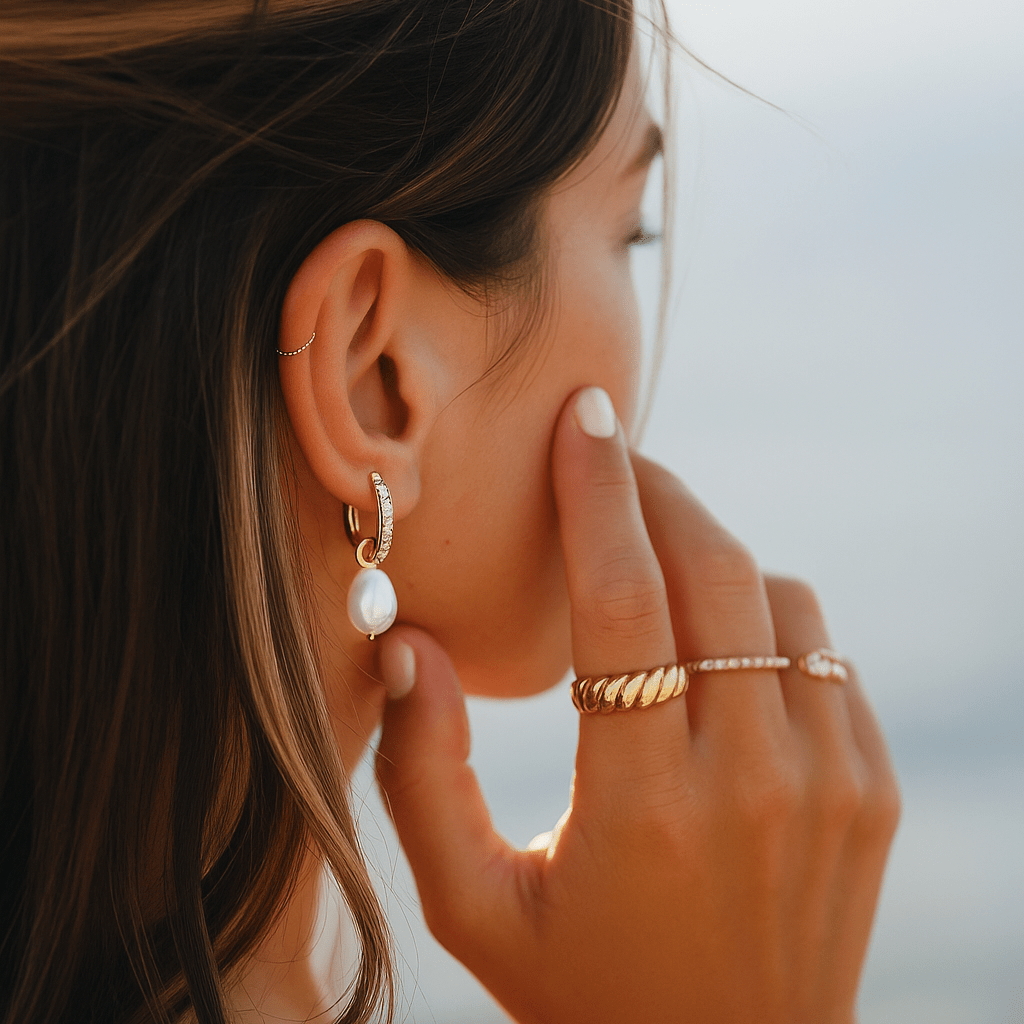Close-up of a woman wearing gold earrings, ring, and bracelet with a blurred background
