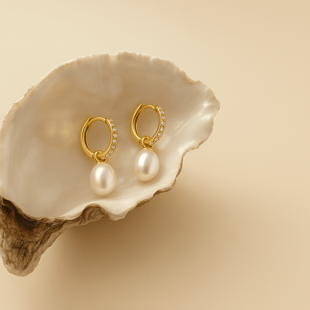 Gold hoop earrings with pearls on a beige shell against a beige background