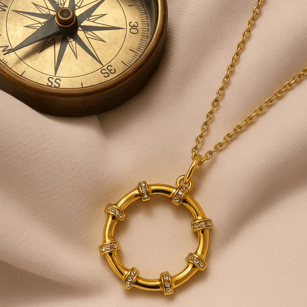 Gold necklace with circular pendant on a beige fabric background