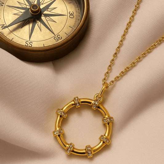 Gold necklace with circular pendant on a beige fabric background