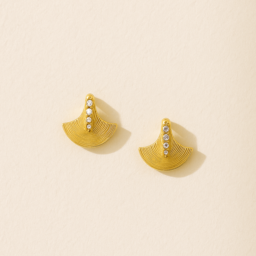 Gold earrings with gemstones on a beige background