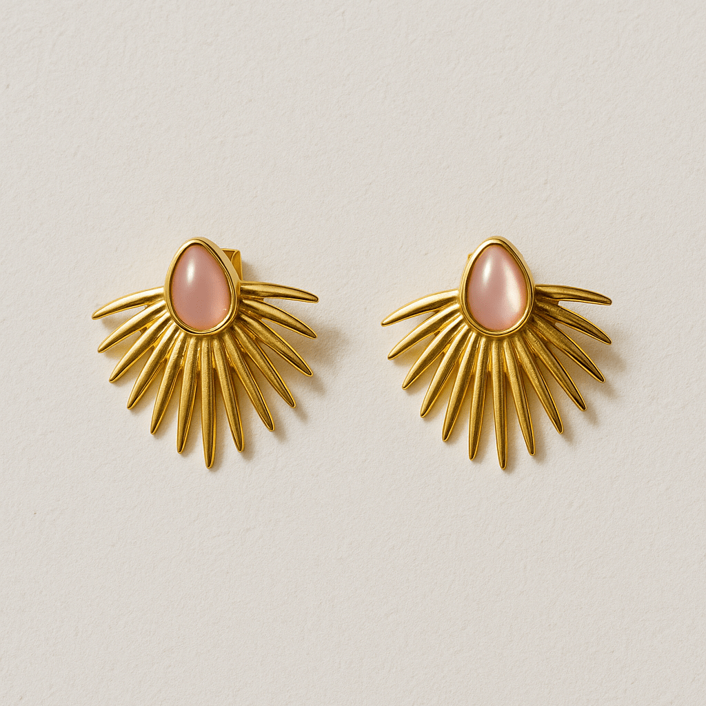 Gold sunburst earrings with pink centers on a beige background