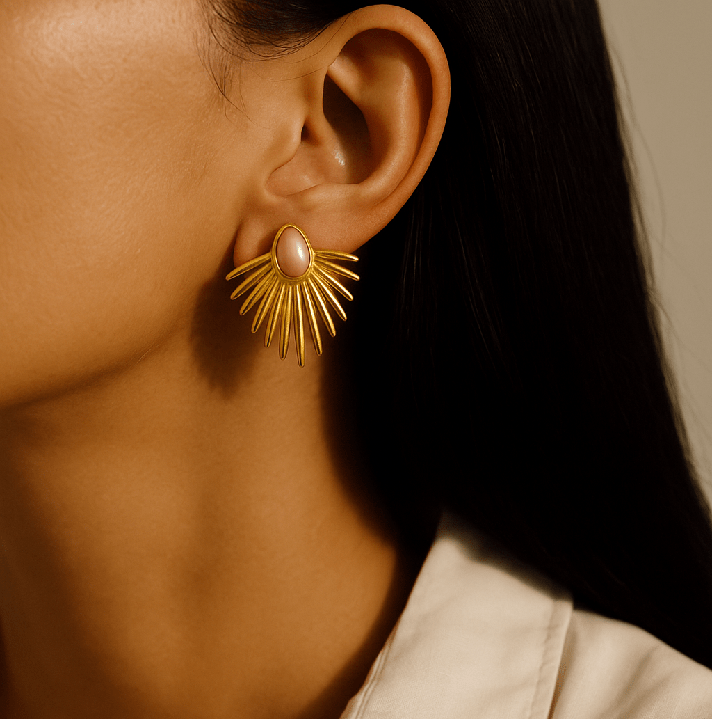 Close-up of a person wearing a gold earring with a pink center.