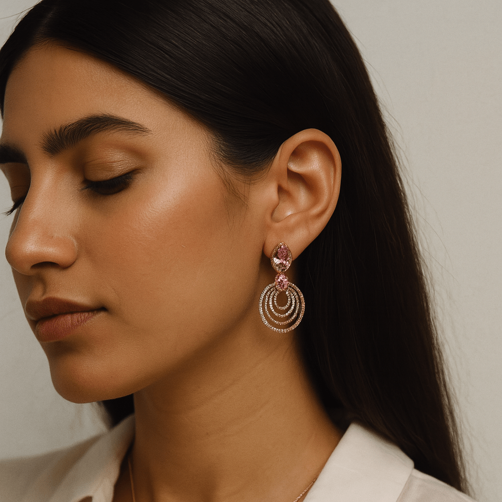 Woman wearing gold and pink earrings with a neutral background