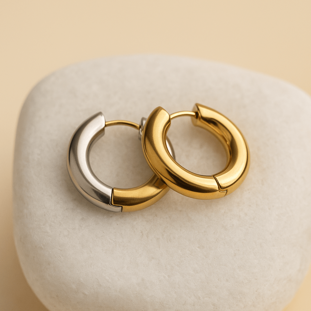 Pair of gold hoop earrings on a textured beige surface
