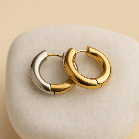 Pair of gold hoop earrings on a textured beige surface