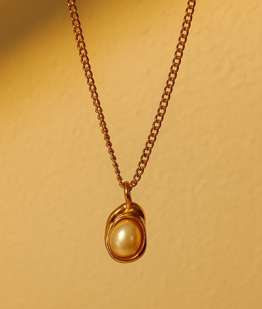 Gold necklace with a pearl pendant on a beige background