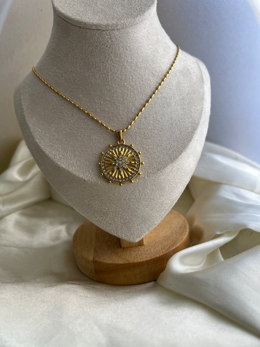 Gold necklace on a mannequin bust with a white garment in the background