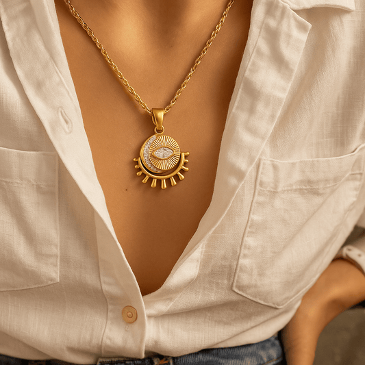 Gold necklace with a circular pendant worn by a person in a white shirt.