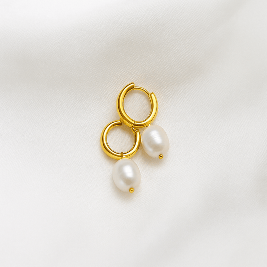 Gold hoop earrings with pearl drops on a light background
