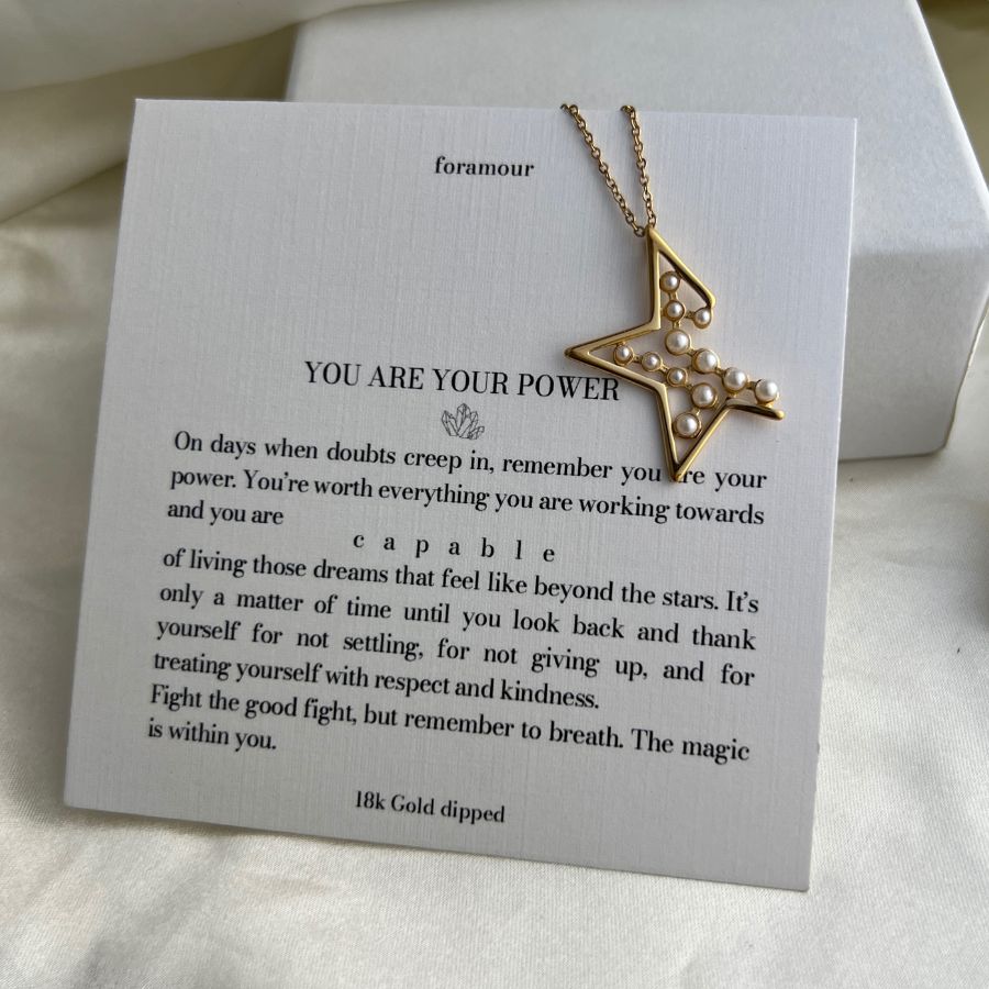 Gold necklace with star design on a card with motivational text
