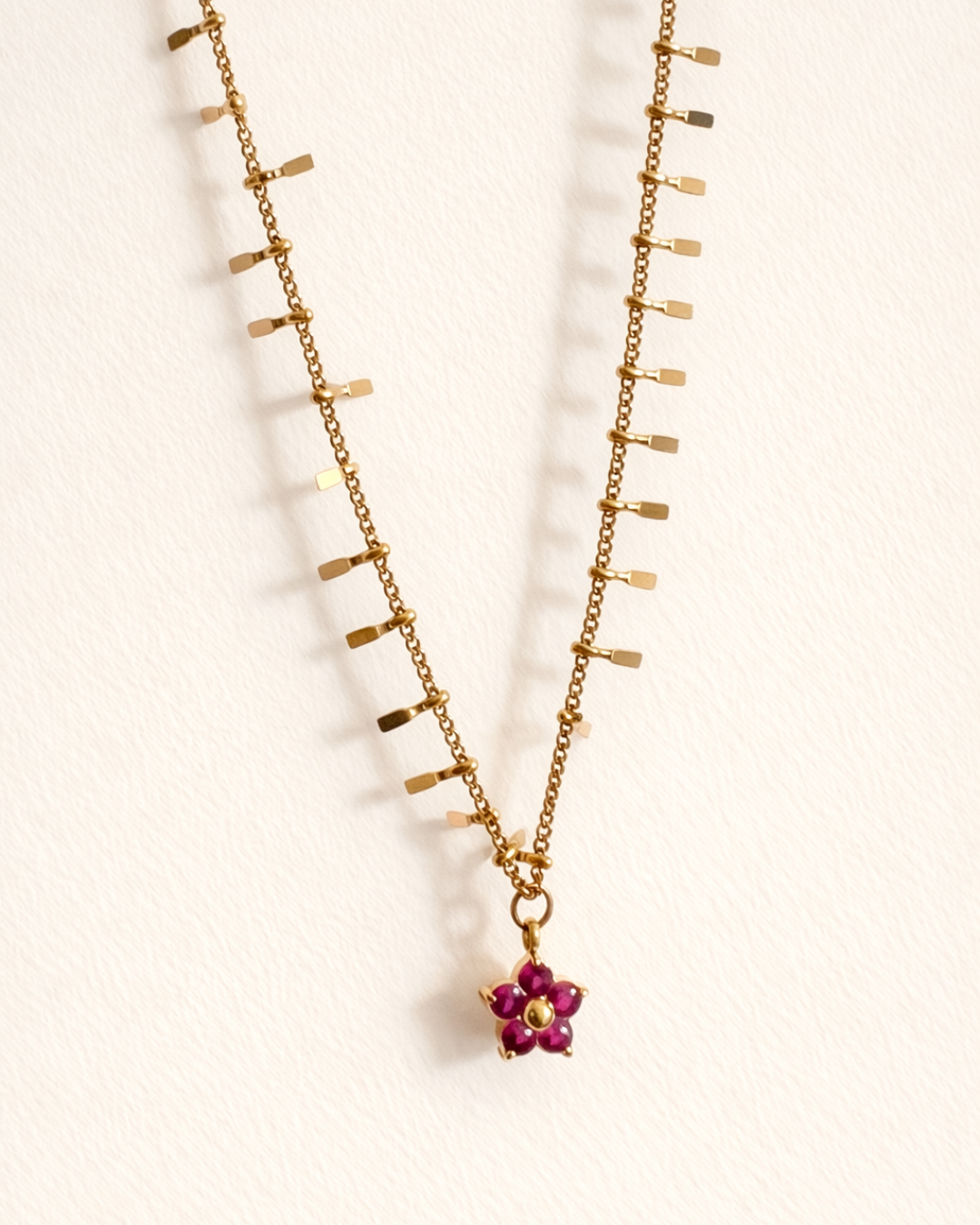 Gold necklace with a floral pendant on a white background