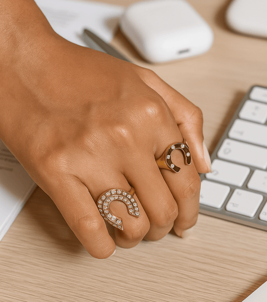 Hand wearing gold rings on a desk with a keyboard in the background