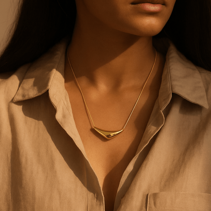 Close-up of a person wearing a gold necklace with a neutral background