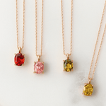 Four gold necklaces with colored gemstones on a white background