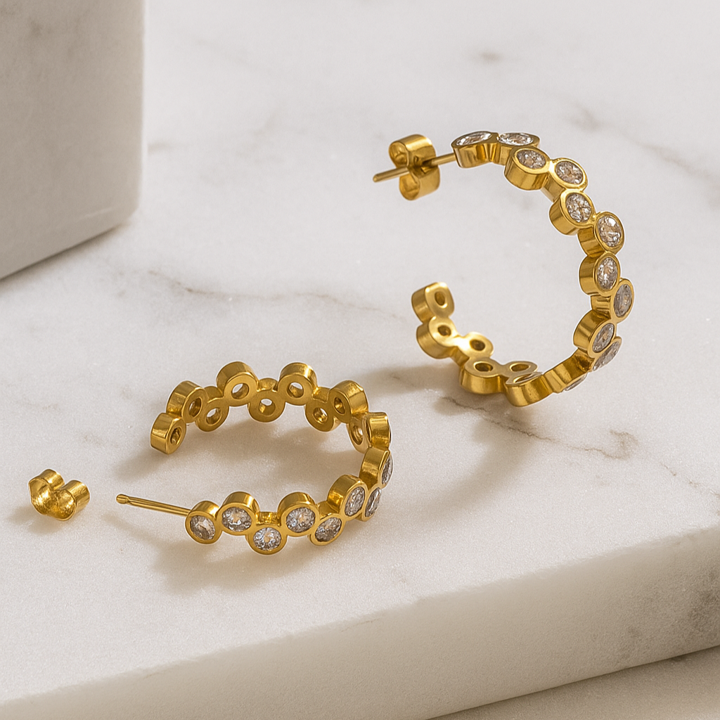 Gold hoop earrings with small diamonds on a marble surface