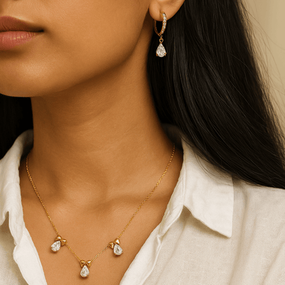 Close-up of a woman wearing gold earrings and necklace with a neutral background