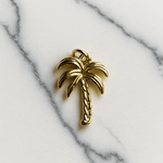 Gold palm tree charm on a marble background