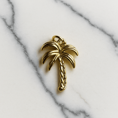 Gold palm tree charm on a marble background