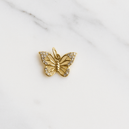 Gold butterfly pendant on a marble surface