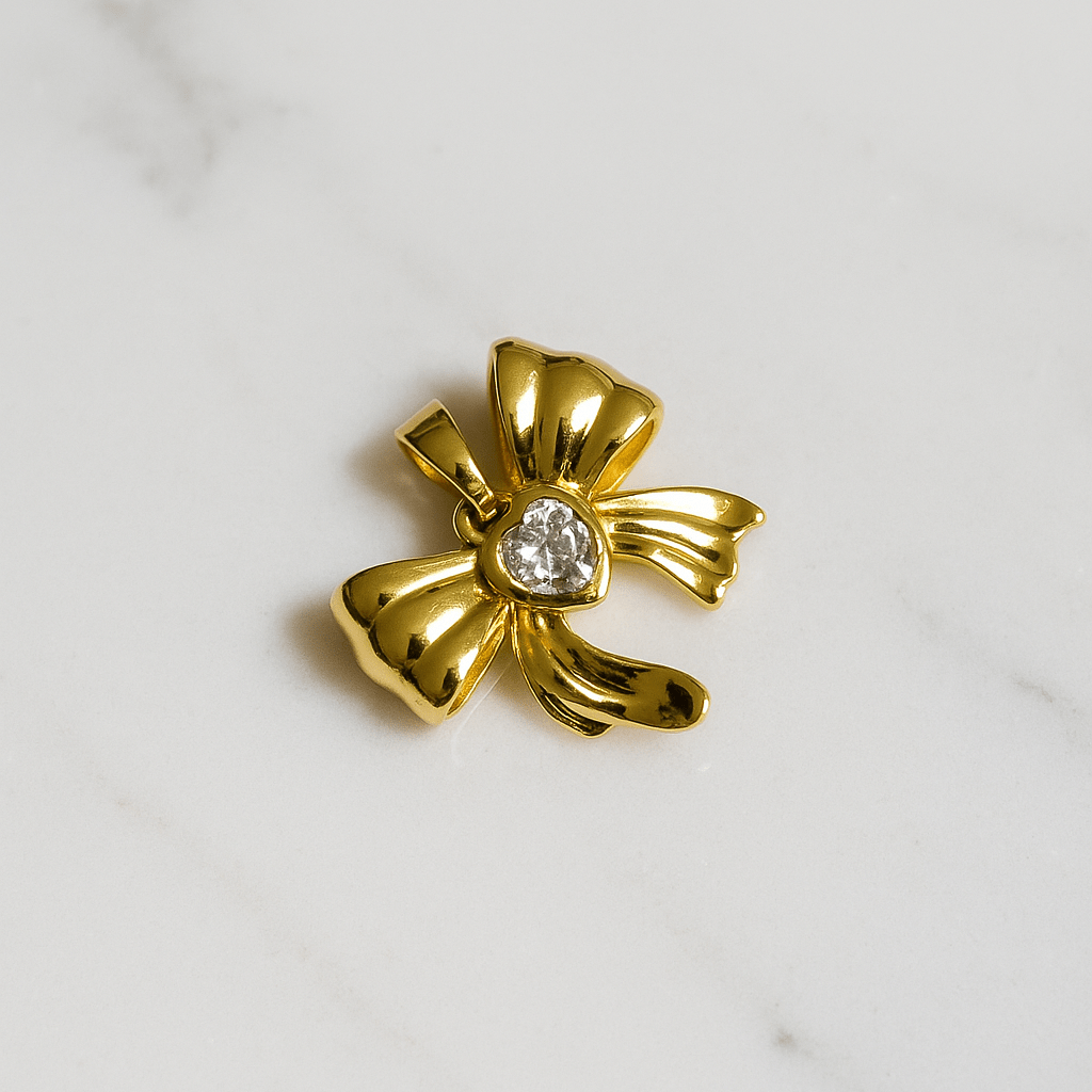Gold bow-shaped brooch with a central gemstone on a marble background