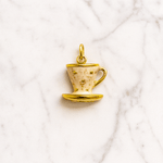 Gold teacup pendant on a marble background