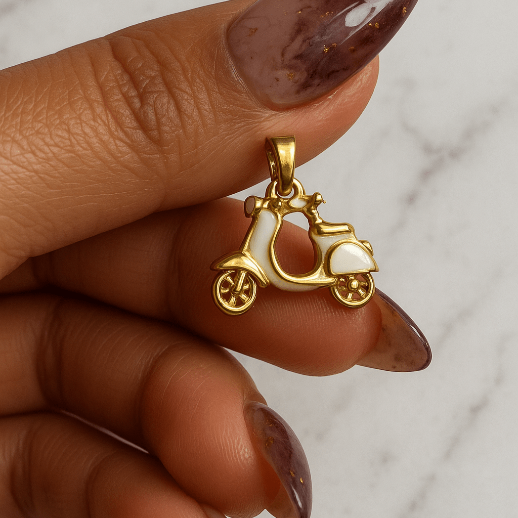 Gold carriage pendant held by a hand with maroon nail polish on a marble background